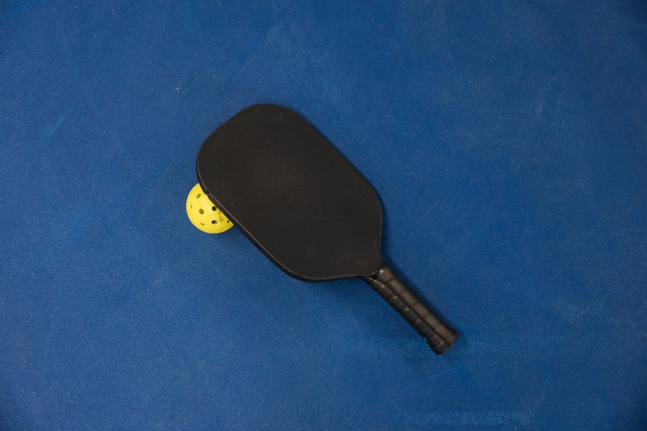 Crafting Captivating Headlines: Your awesome post title goes here A pickleball paddle and ball on a textured blue surface, showcasing sports equipment.
